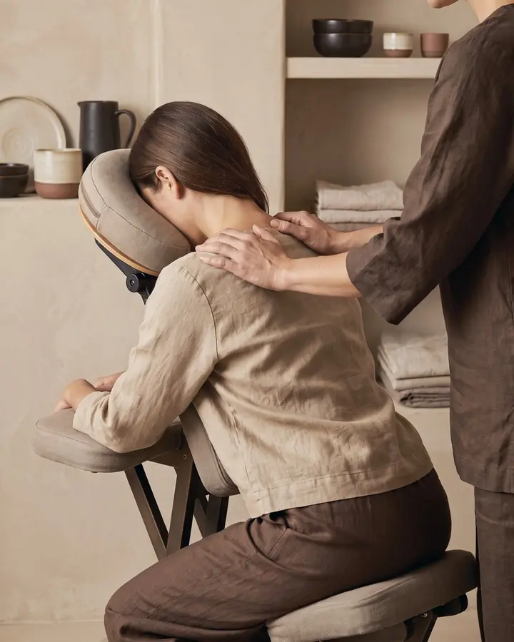 Neck and shoulder massage: a female client sitting leaned forward in a massage chair
